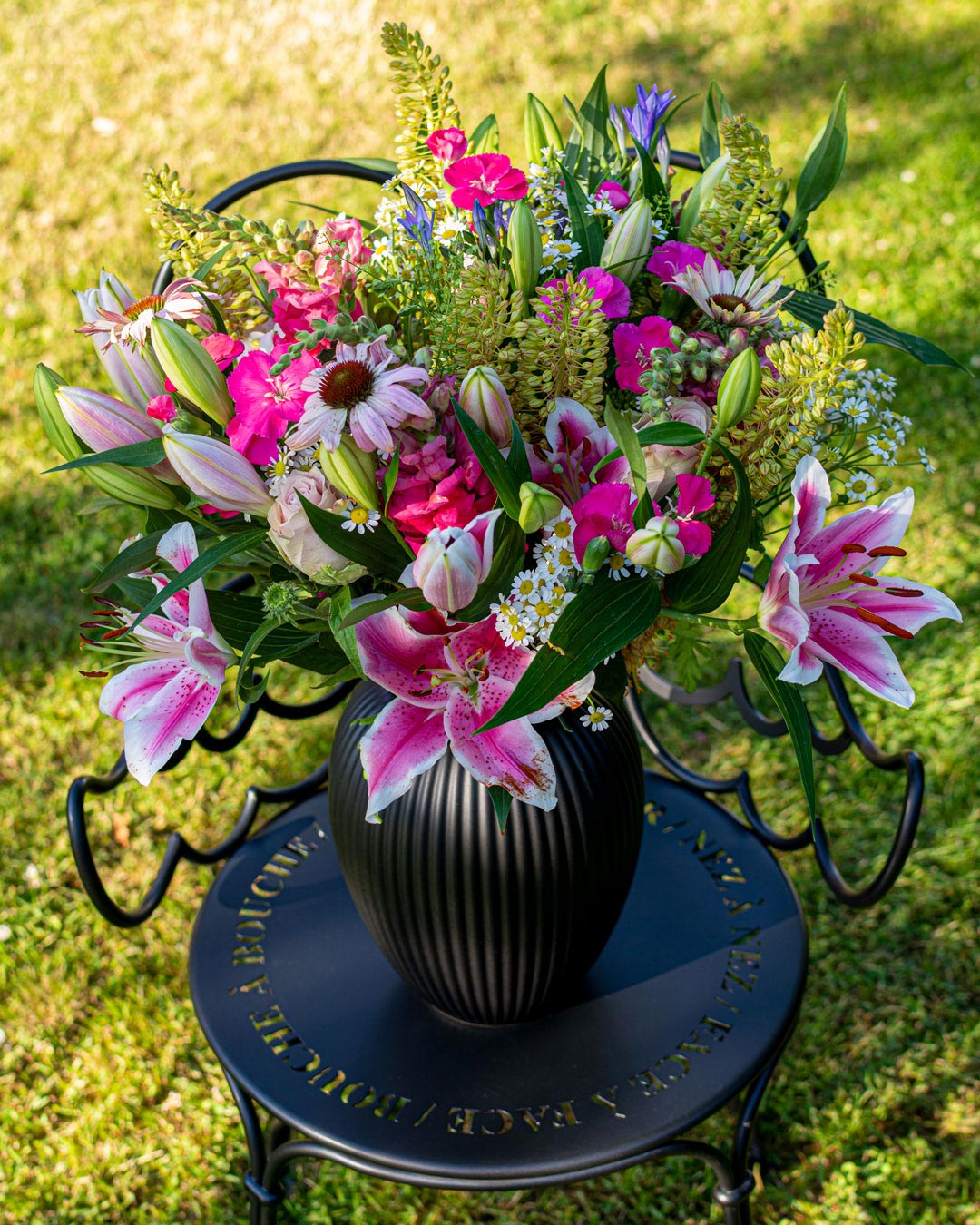 Sort vase fra Michael Andersen Keramik med blomster på smedejernsstol i haven